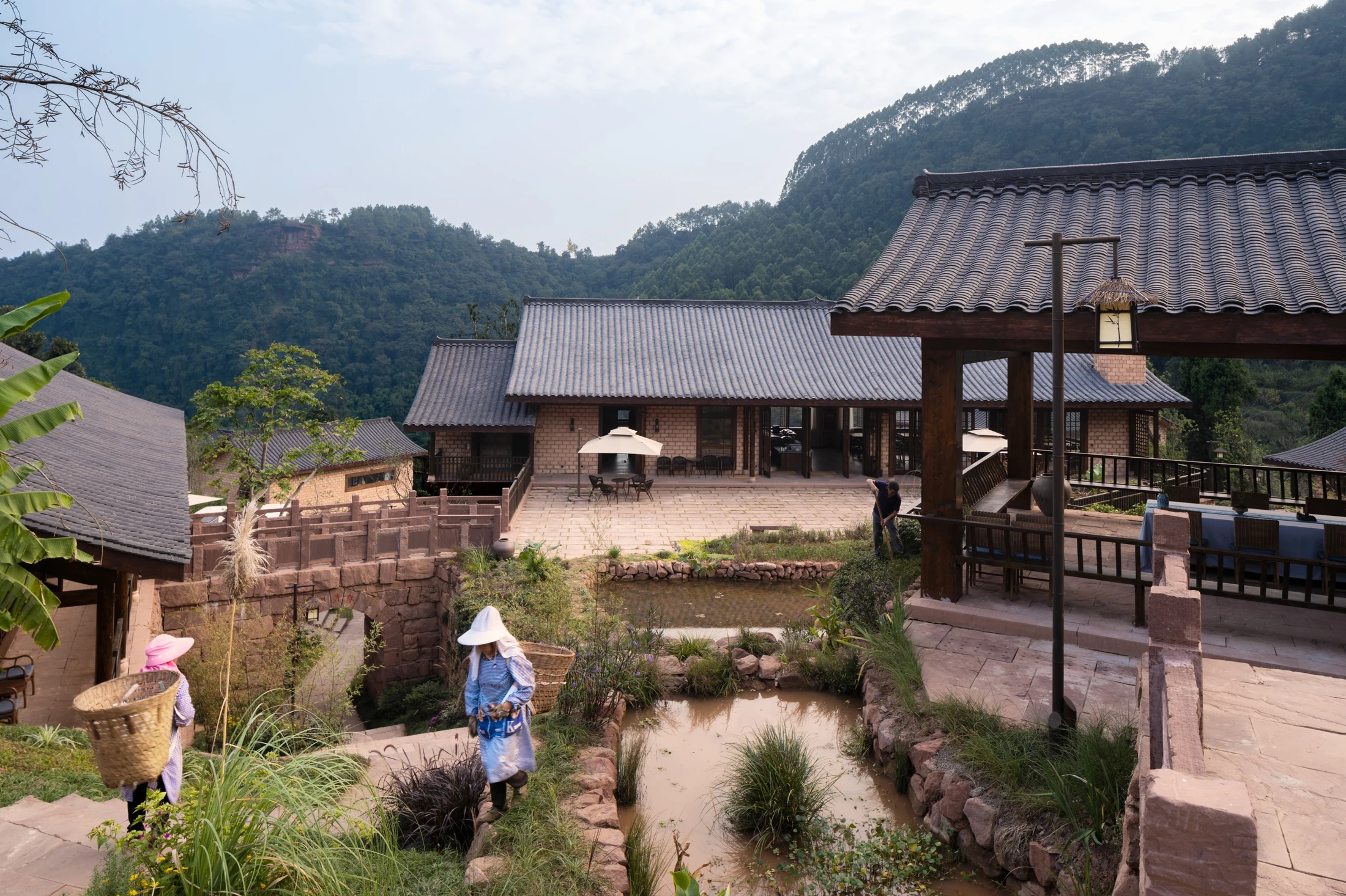 People walking along paths between tiled-roof buildings and planted courtyard spaces