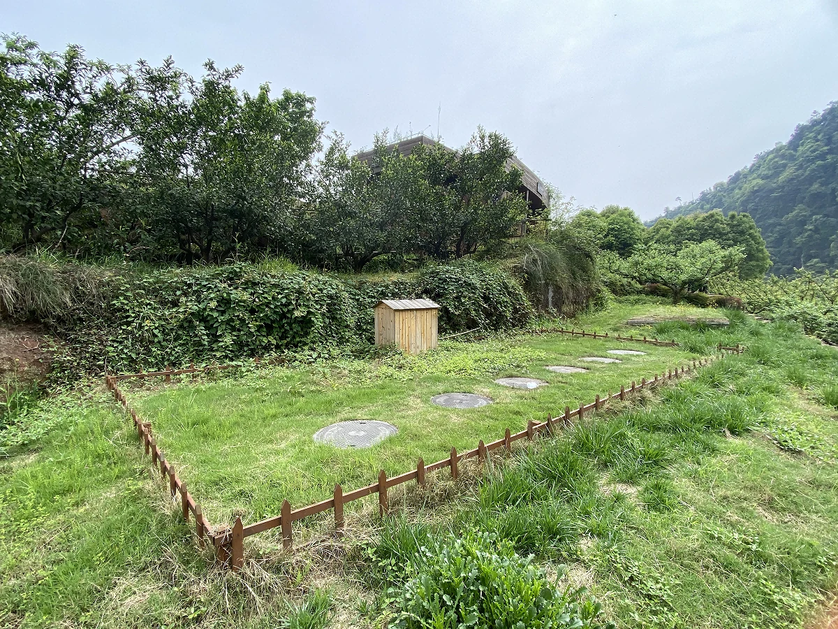 Grass-covered wastewater treatment area with circular access covers in the landscape